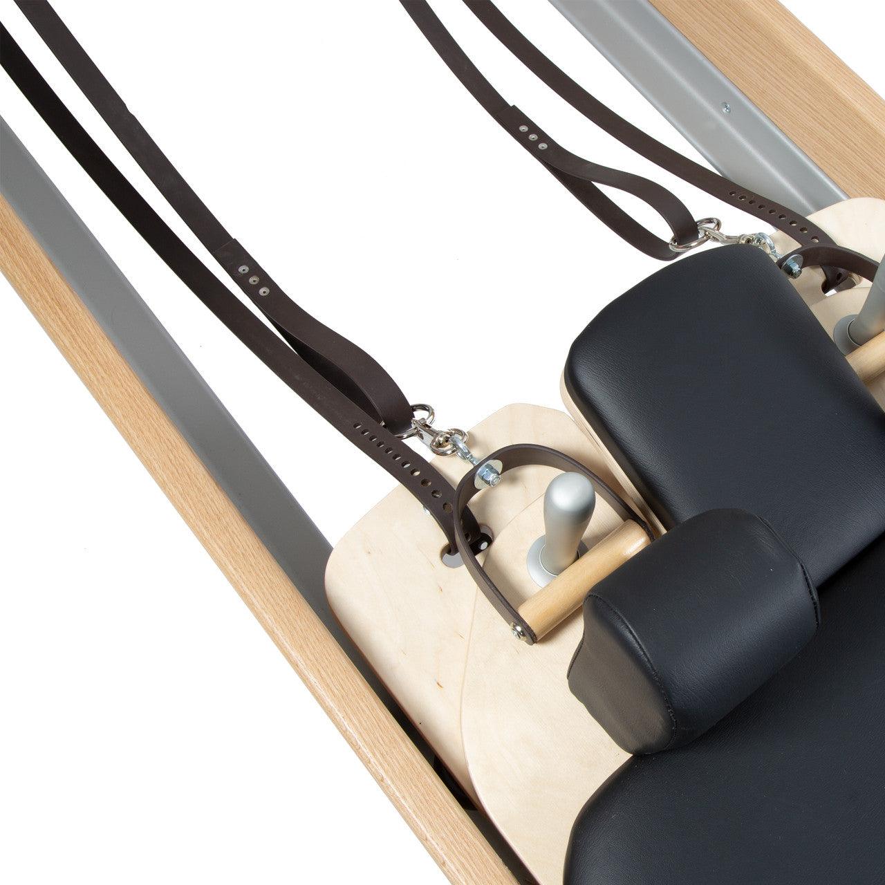 Close-up of wooden carriage and footbar details on a luxury Pilates reformer.